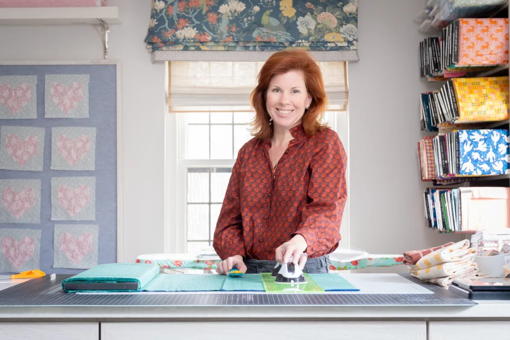 Kate Eichhorn, owner of Golden Girls Fabric Co., in her workspace surrounded by bolts of fabric