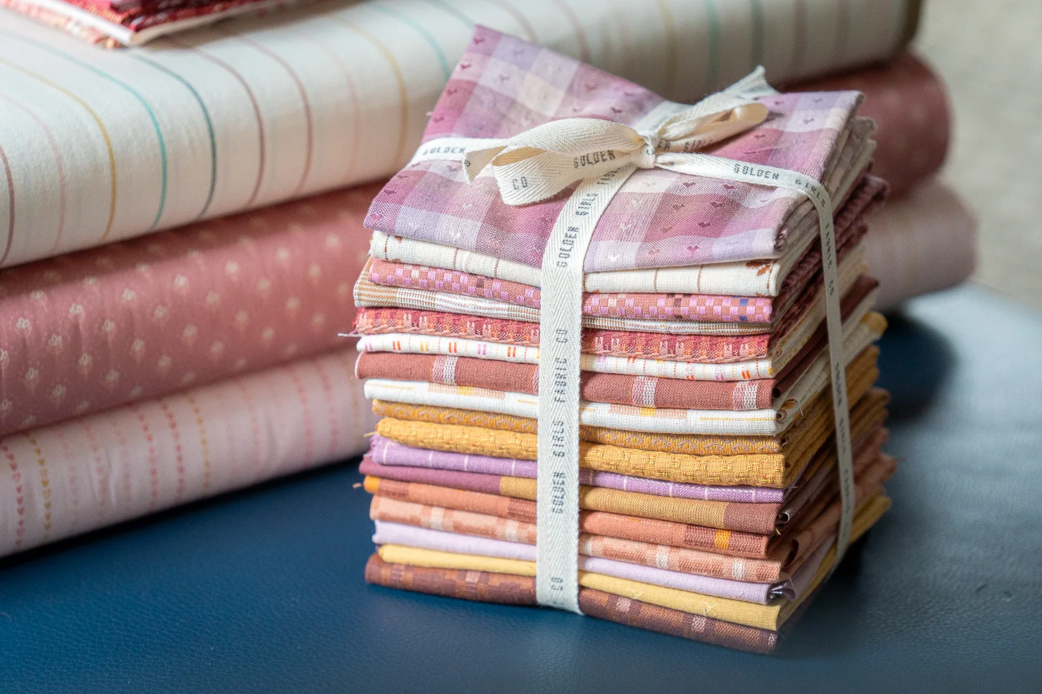 a stack of fabric from Golden Girls Fabric Co. in a variety of pink hues