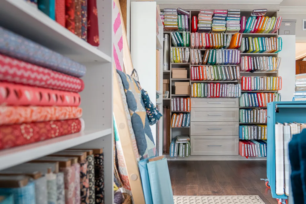a room filled with brightly colored fabrics stacked on shelves