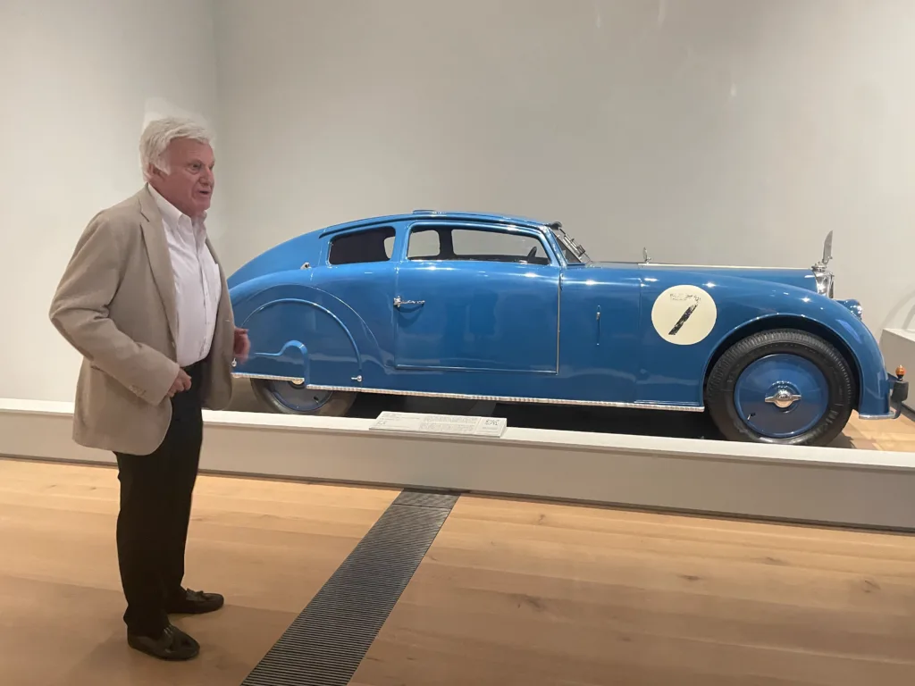 Guest curator Ken Gross informs guests about a Voisin vehicle during a preview of "Roaring: Art, Fashion, and the Automobile in France, 1918–1939."