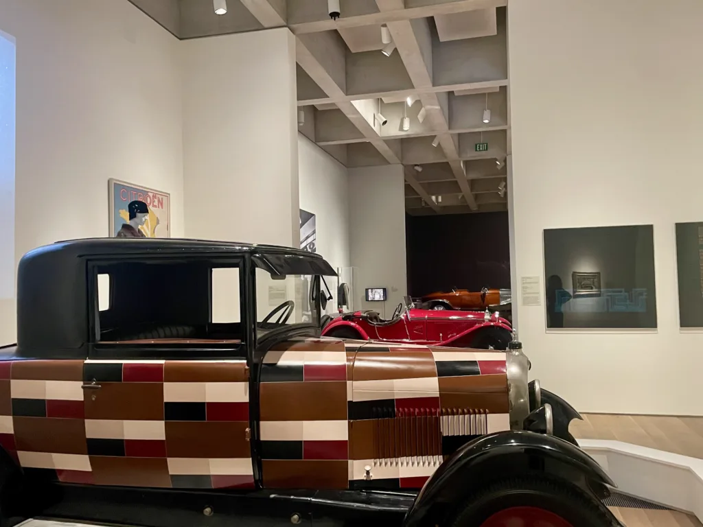 Vintage vehicles are parked in the Saint Louis Art Museum's galleries as part of Guest curator Ken Gross informs guests about a Voisin vehicle during a preview of "Roaring: Art, Fashion, and the Automobile in France, 1918–1939."