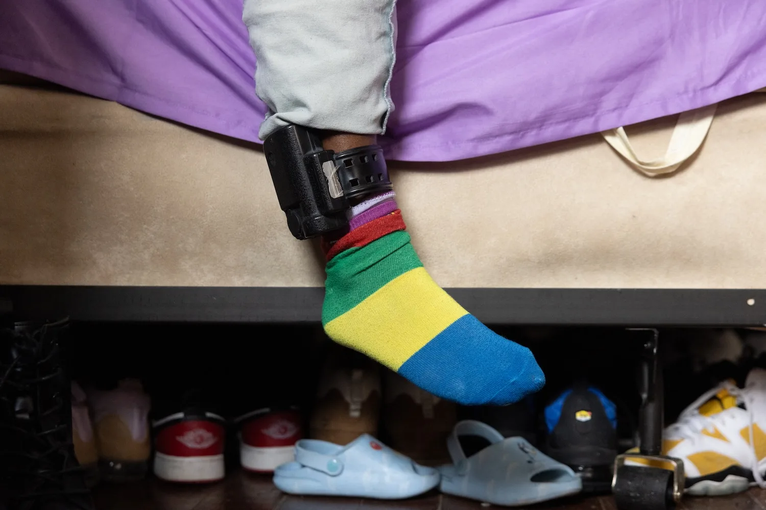 Khyla Mason, 22, sits in her room at her mother’s house, with an ankle monitor exposed above her striped sock.