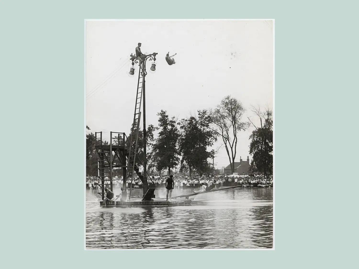Divers improvise a high-dive platform from the top of a light pole at Fairground Park’s pool.