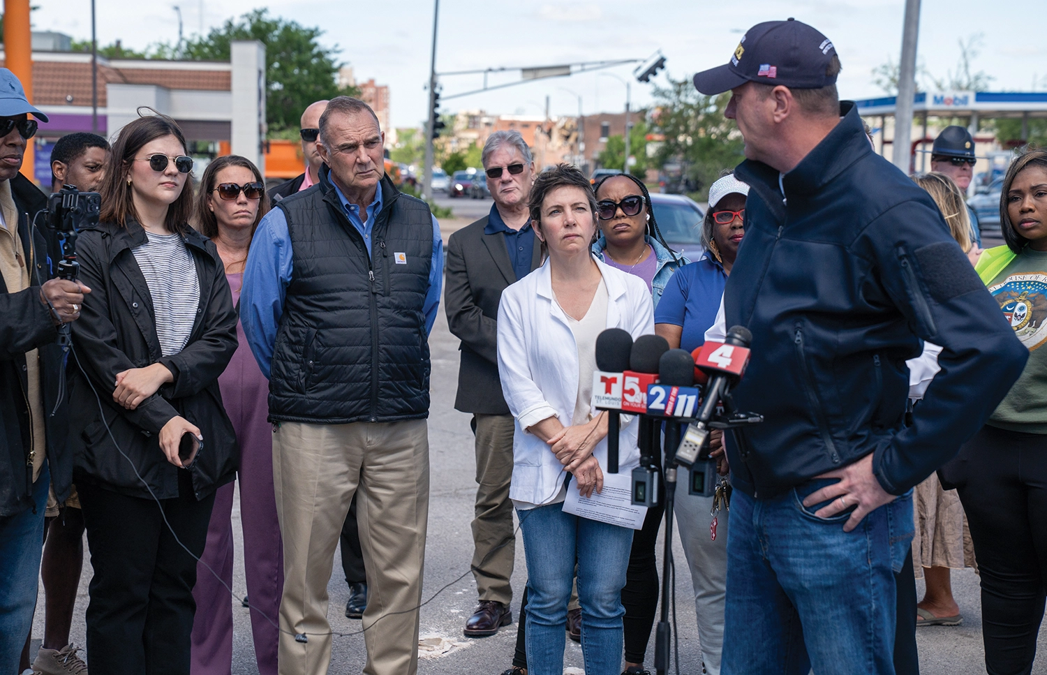 Missouri Gov. Mike Kehoe and St. Louis Mayor Cara Spencer watch as Missouri Senator Eric Schmitt delivers an update on disaster response in St. Louis on May 17, 2025. The previous day a tornado caused severe damage to the city’s north side.