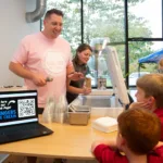scooping ice cream at social with an open computer with QR code