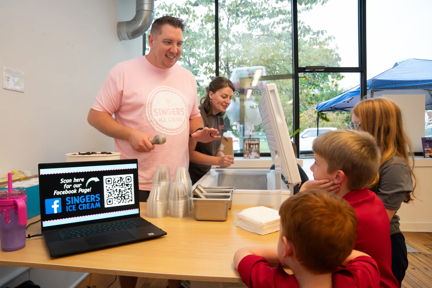 scooping ice cream at social with an open computer with QR code