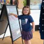 child pointing to sign at the SLM ice cream social