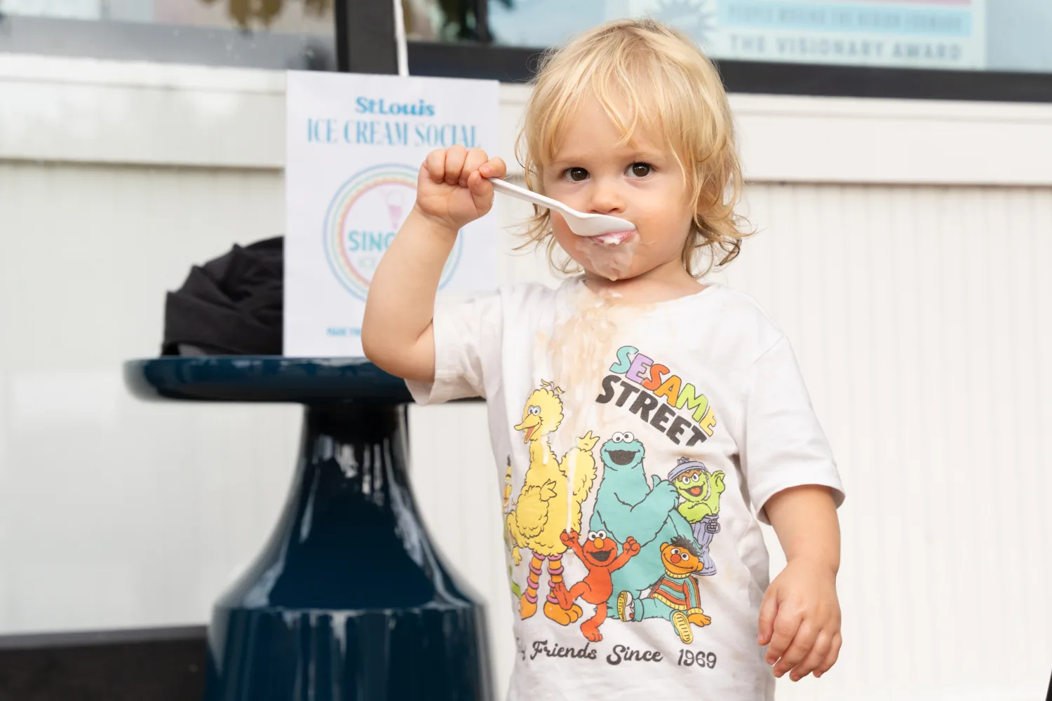 Child eating ice cream at the ice cream social wearing a Sesame Street shirt