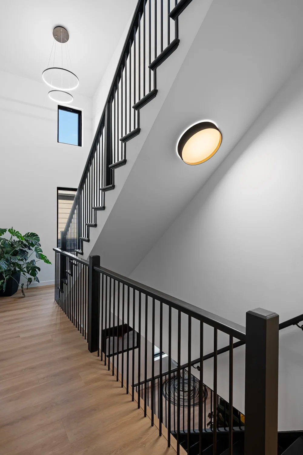 Custom open staircase with black steel railing and modern light fixtures designed by Campbell House and Home.