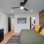 Primary bedroom designed by Campbell House and Home featuring a slatted wood accent wall and warm color palette.