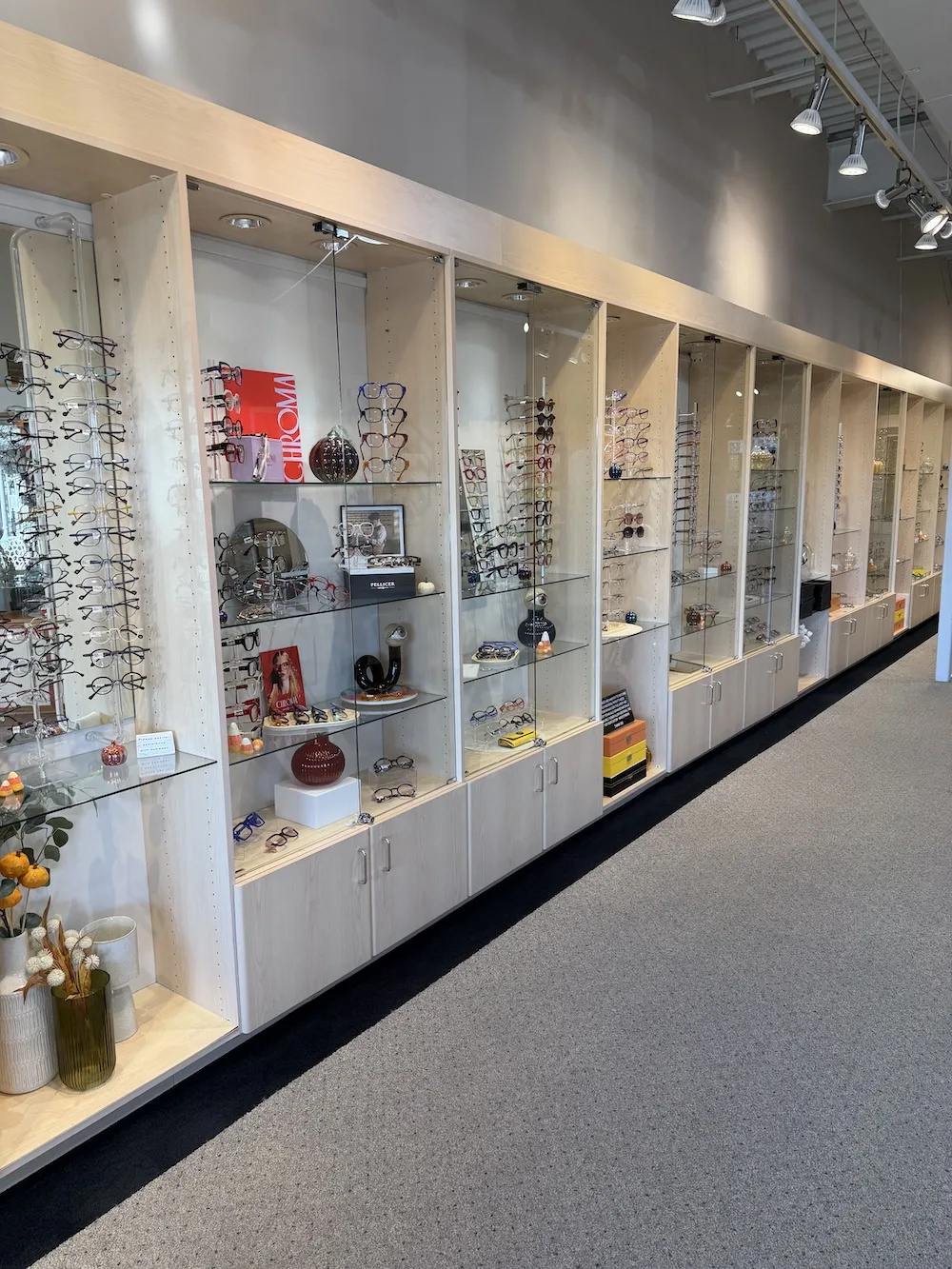 A glass display case filled with colorful eyeglass frames in a variety of shapes and styles, all available at Eyewearhaus.