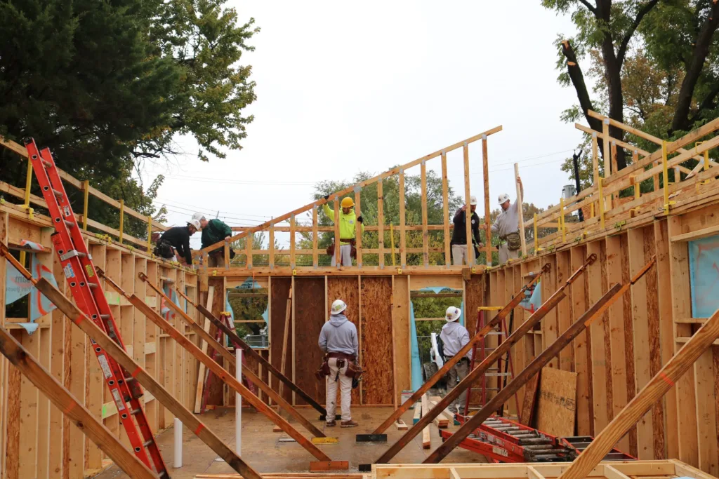 Volunteers build and secure the wooden frame of a new house at a Habitat for Humanity Saint Louis site.