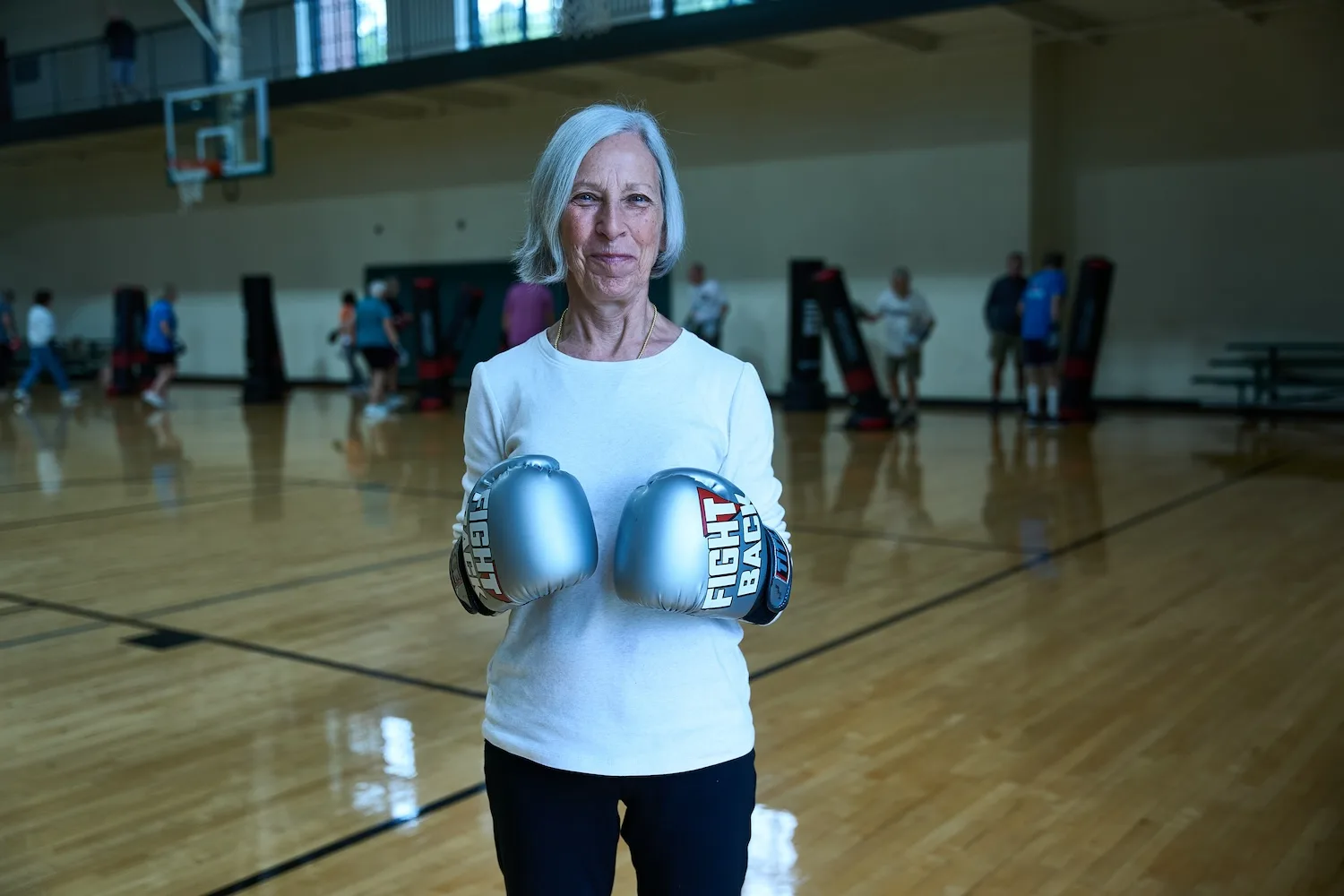 Mary Eagan faces the camera showing boxing gloves that read "Fight Back."