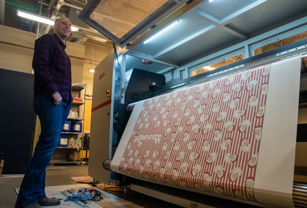 A man in front of a large printer
