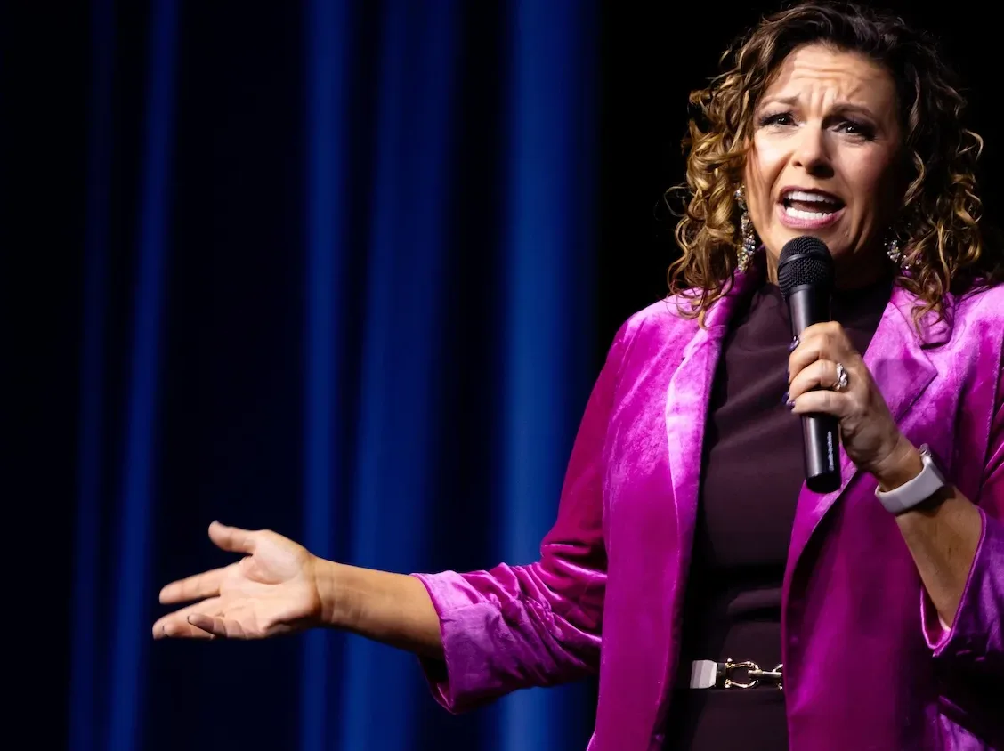 A woman on stage holds a microphone.