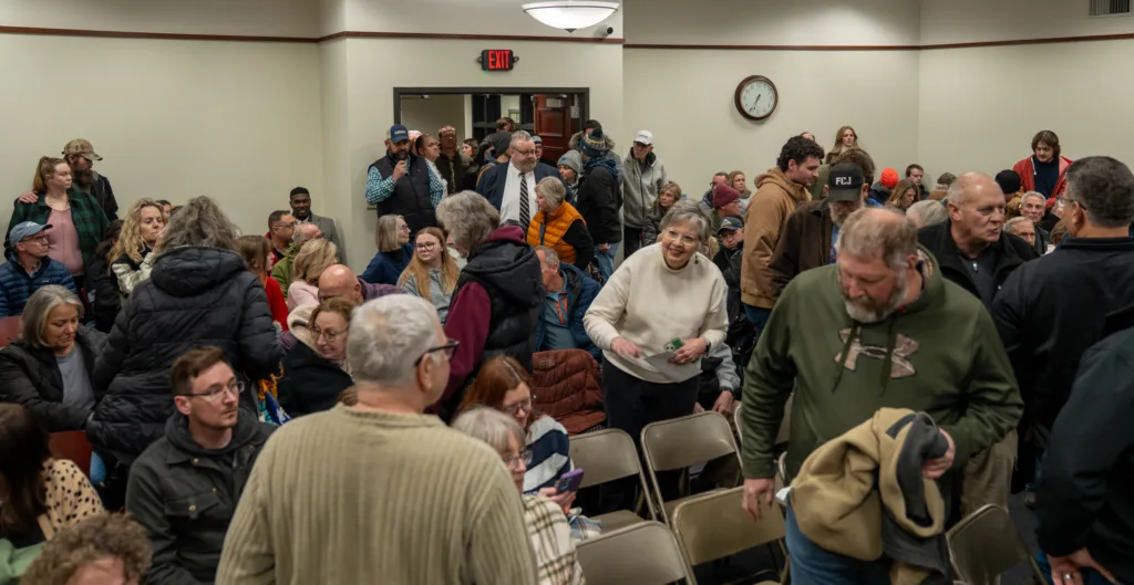 A crowd files into a meeting room.
