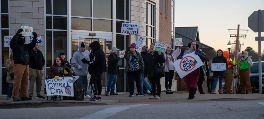 People with signs rallying in front of a building