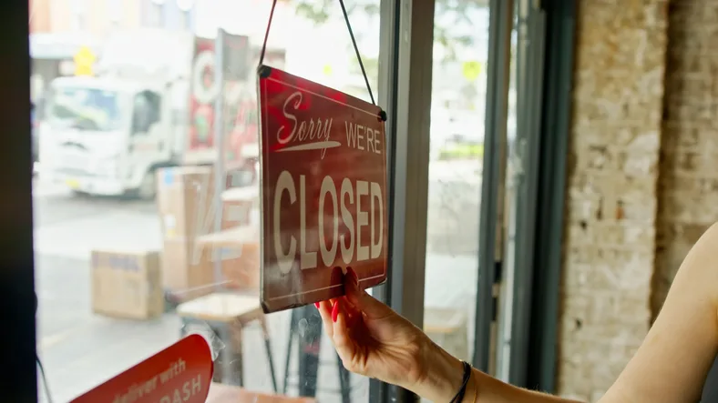Hand Turning Sign to Open in Restaurant Window