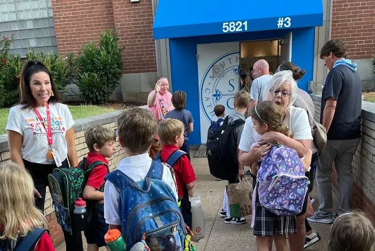 Teachers and students standing by a school entrance.
