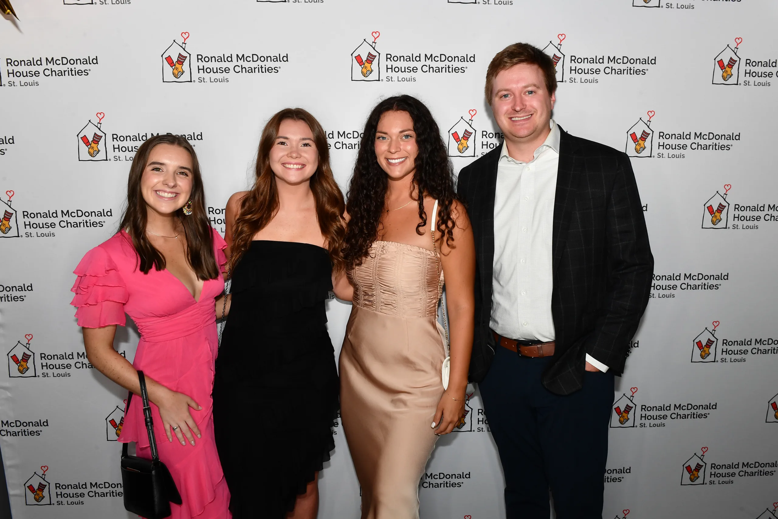 Guests pose for a photo in front of the Ronald McDonald House Charities of St. Louis step-and-repeat backdrop at a Red Shoe Society event.