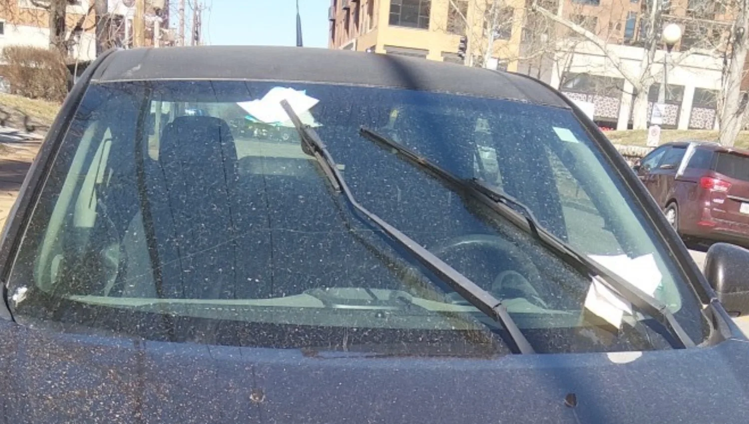 A dirty car with multiple parking tickets on its windshield.