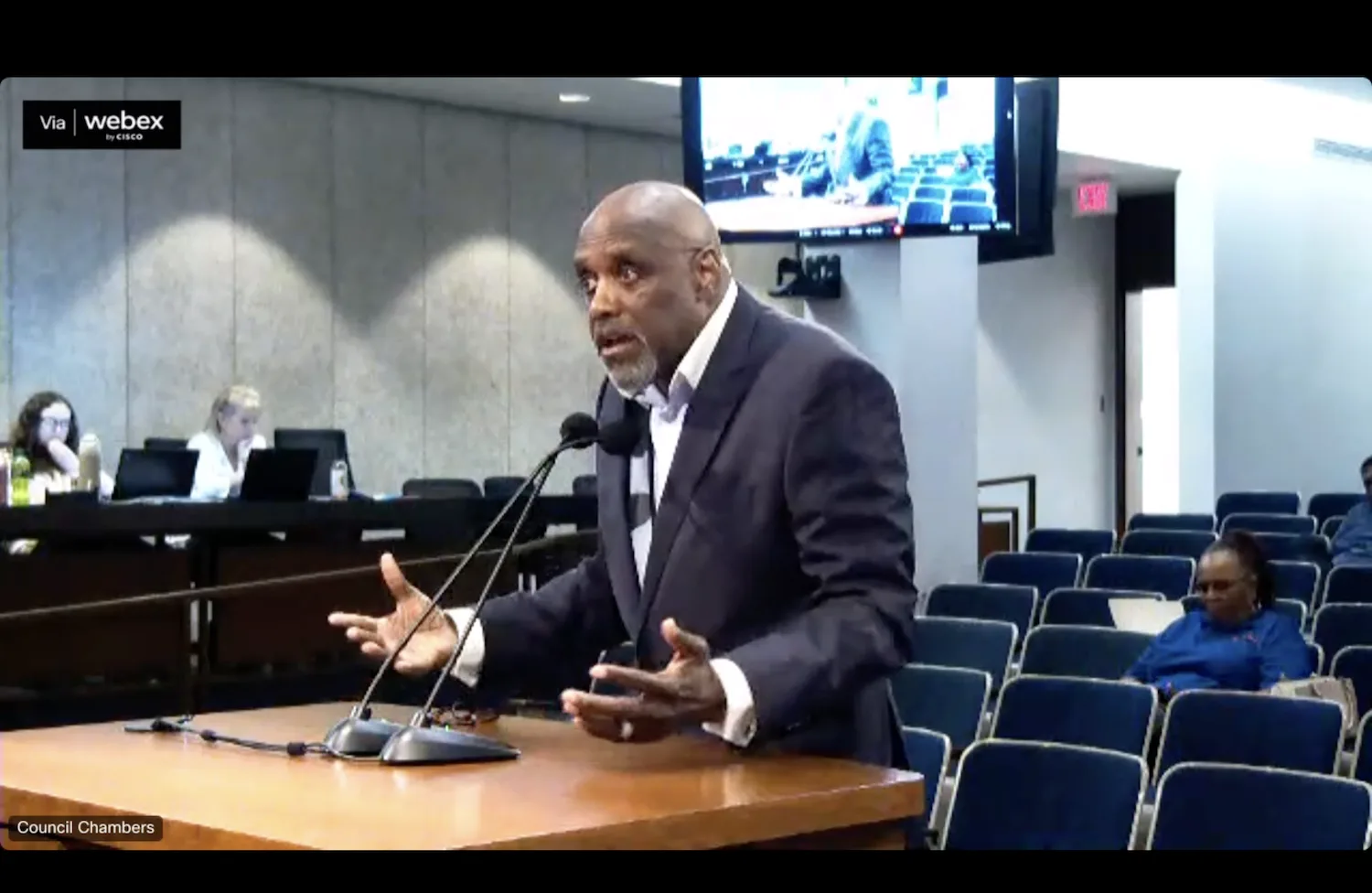 A man speaks into a microphone at a public hearing.