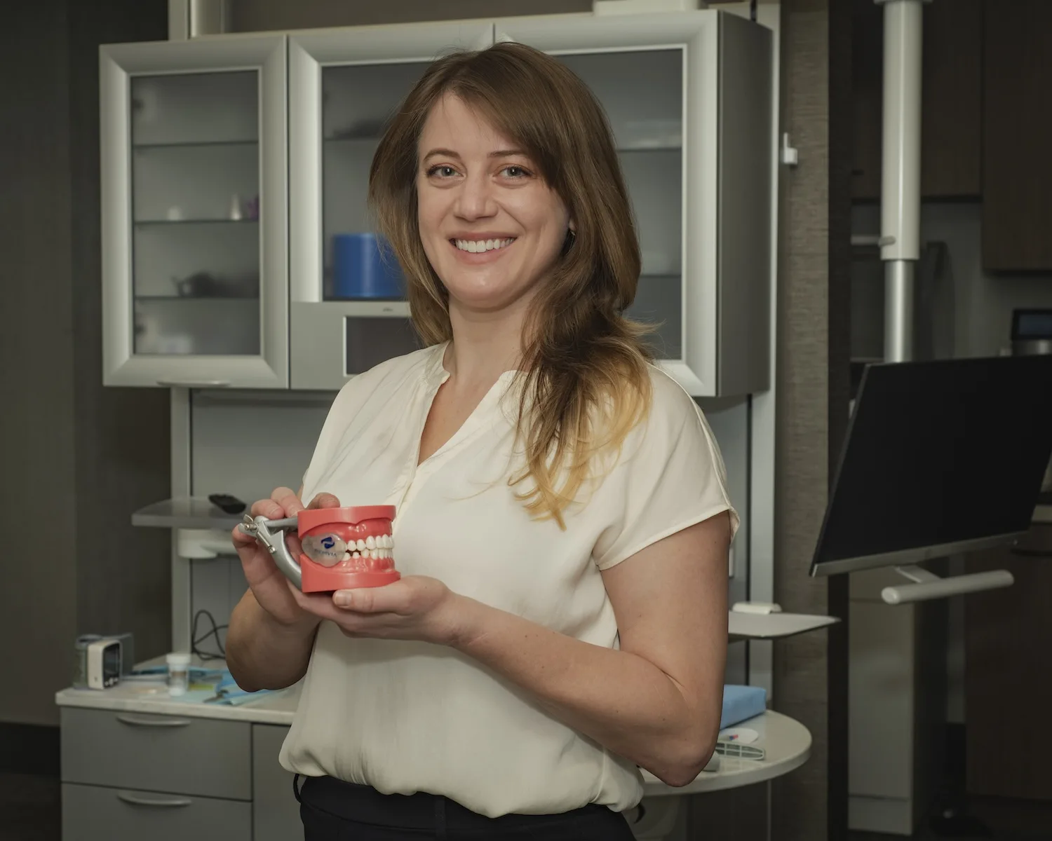 A woman holds a mouth guard.