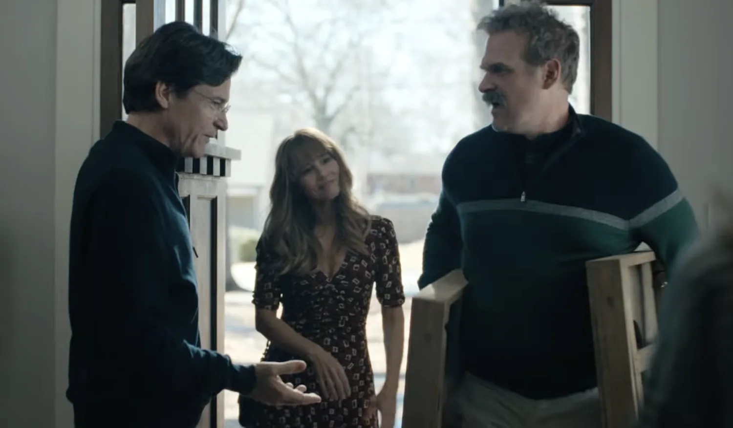 Two men stand in a doorway, with a woman behind them.