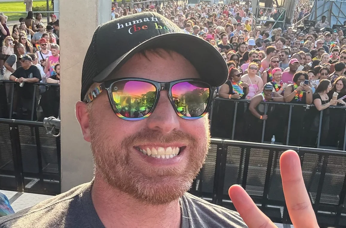 A man wearing sun glasses flashes the peace sign.