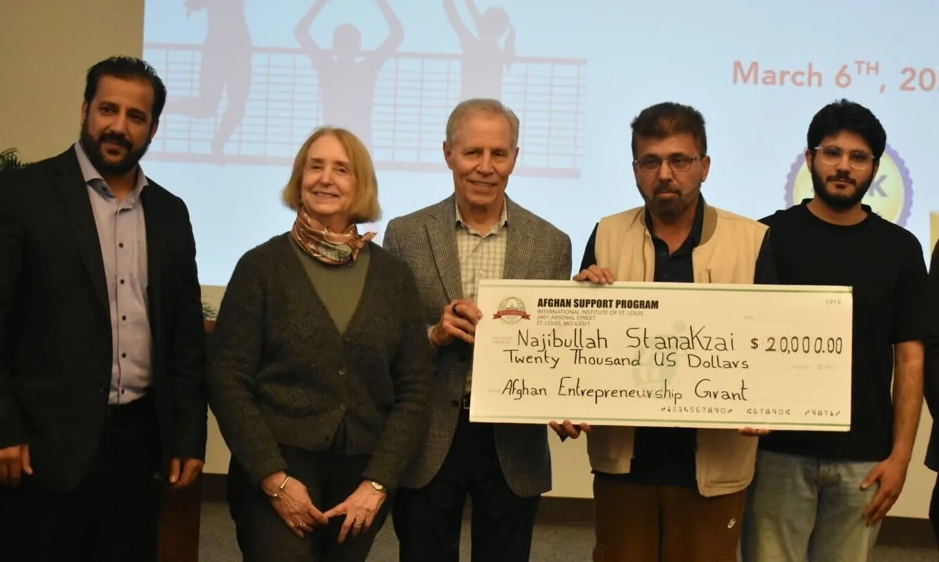 Five people surround a man holding a check for $20,000.