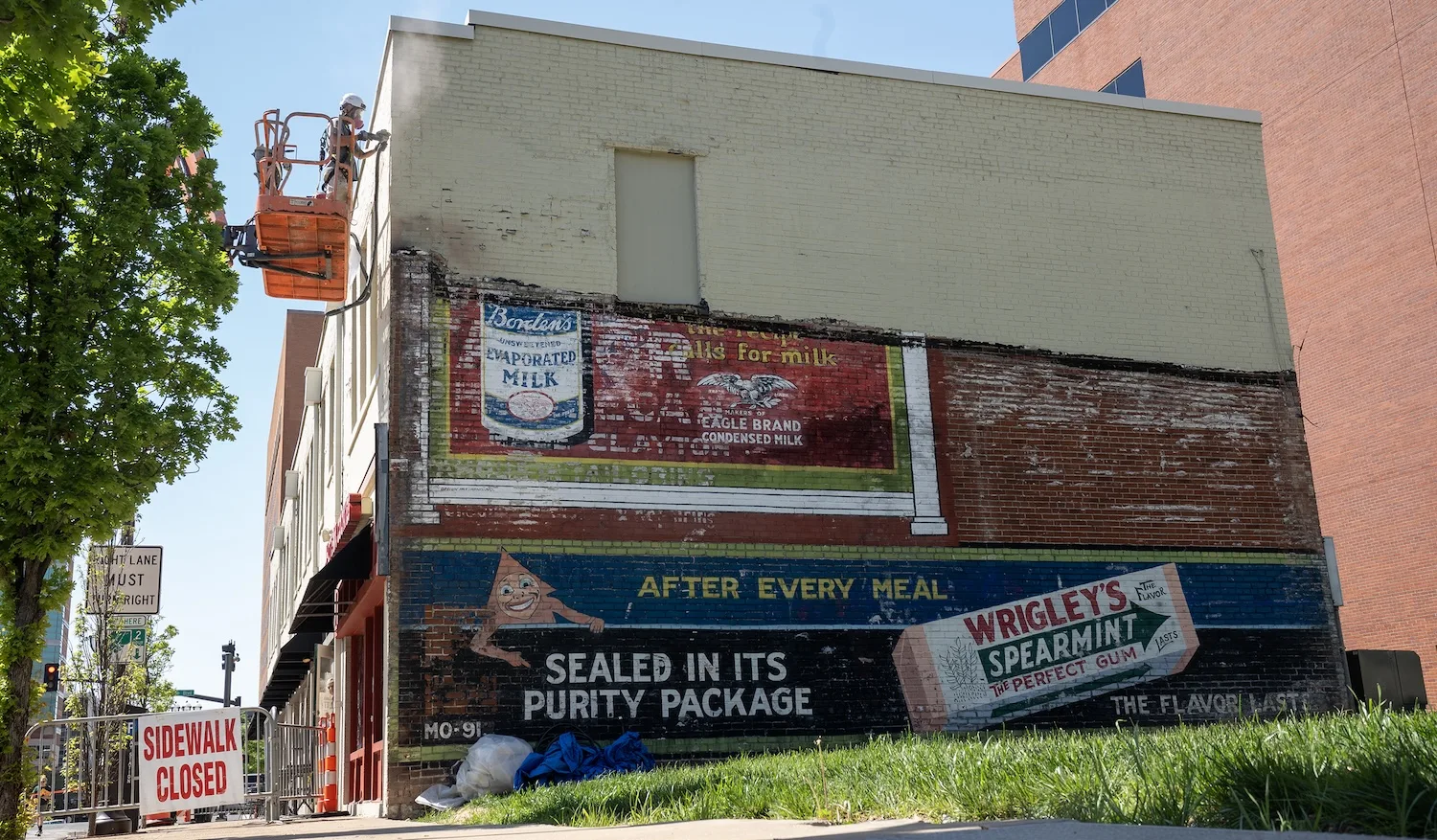 A mural for Wrigley's Spearmint and Borden's Unsweetened Evaporated Milk is visible on the lower half of a brick wall.