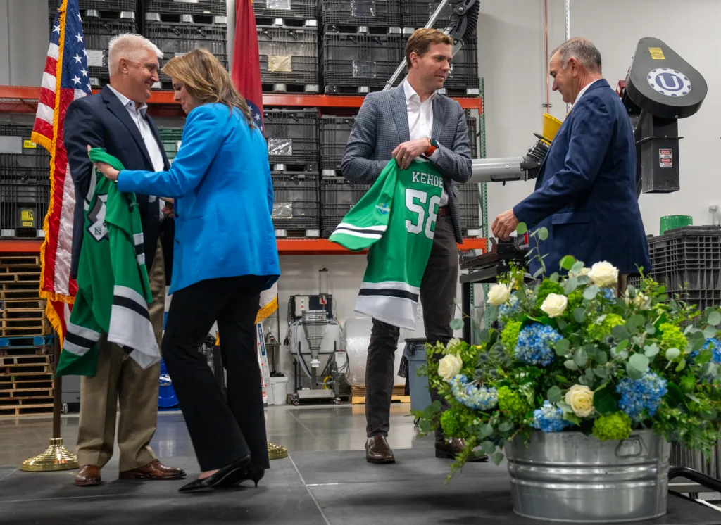 A man gives another man a hockey jersey