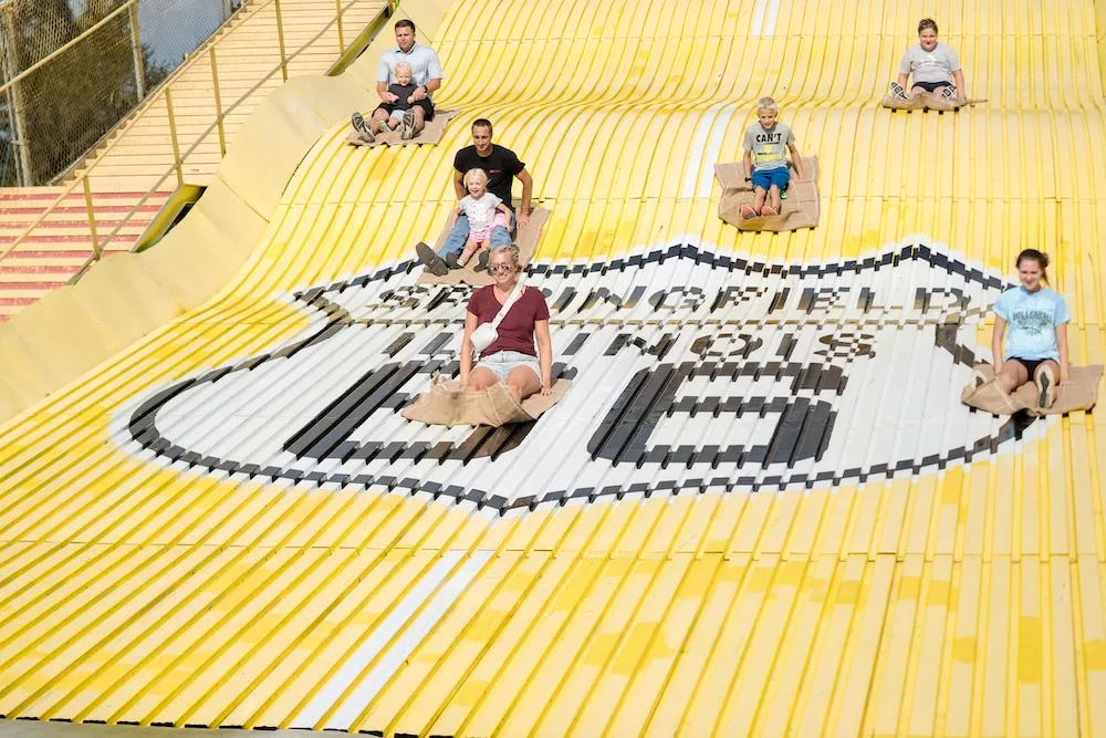 Families race down the iconic yellow slide at the state fairgrounds.
