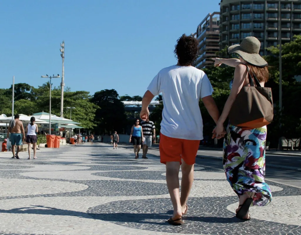 A couple walk through a plaza on a sunny day.