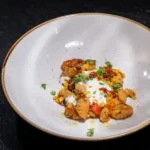Primo | ricotta gnocchi + spring vegetables + chili crisp + stracciatella + basil oil