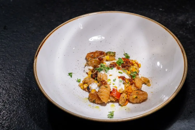 Primo | ricotta gnocchi + spring vegetables + chili crisp + stracciatella + basil oil