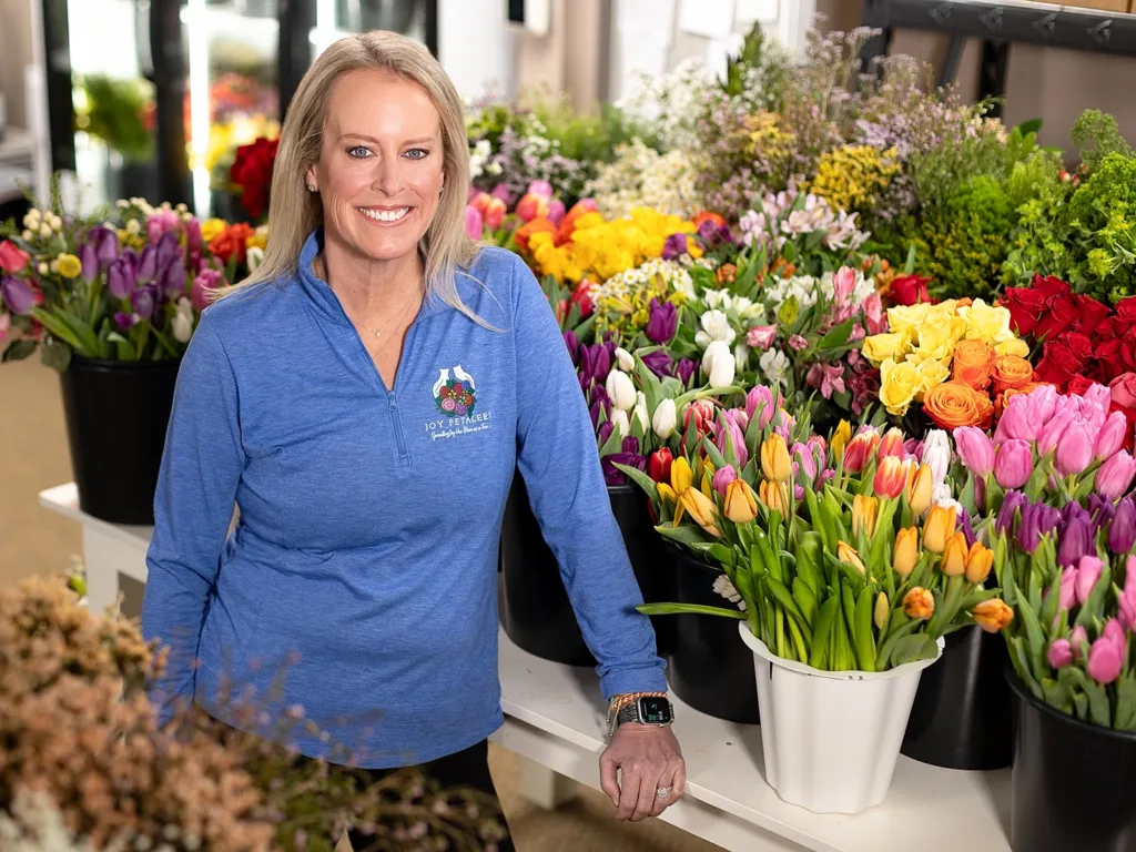 Colleen O'Neill Rohm stands beside a table of donated flowers.