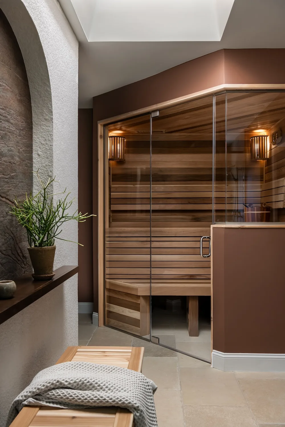An angled sauna and angled shower were positioned across from each other, organizing the bathroom around a central stone veneer feature wall.