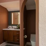 Arched walkways frame the vanity and lavatory spaces, helping the room reveal itself gradually instead of showing every feature at once.