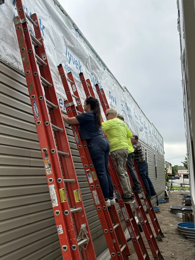 Habitat for Humanity volunteers install exterior siding during a neighborhood home build project.