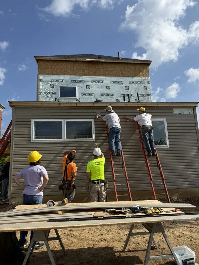 Habitat for Humanity volunteers install exterior siding during a neighborhood home build project.
