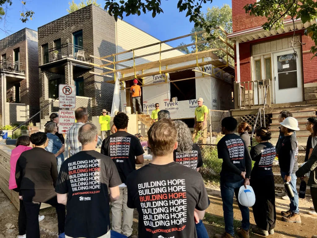 Volunteers gather at a Habitat for Humanity build site to receive instructions and assignments before beginning the day’s work.