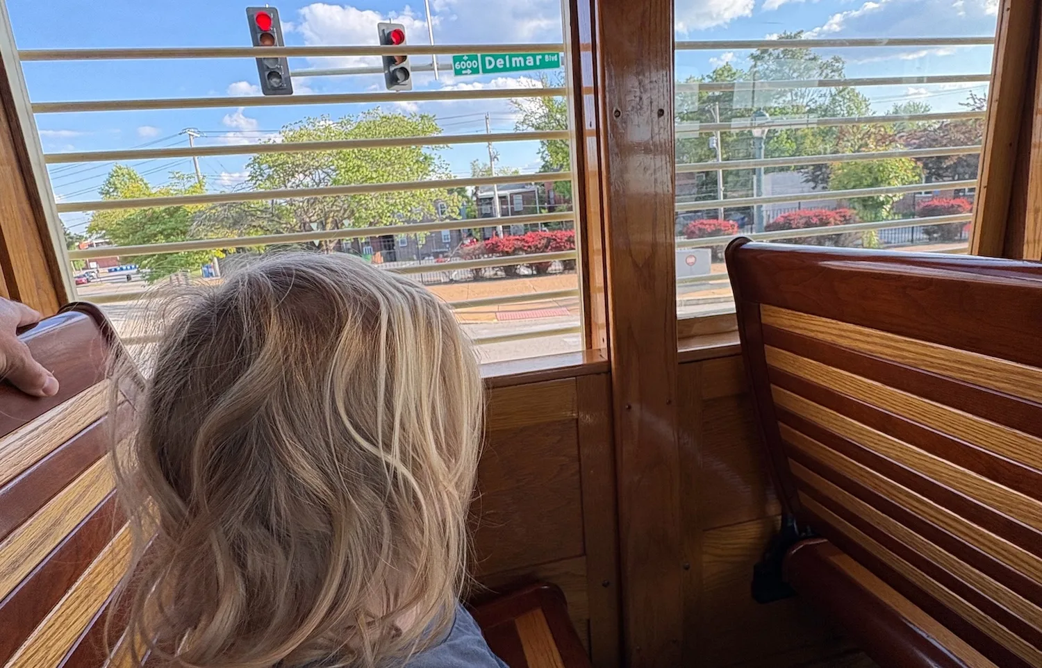 A small boy with blond hair looks out the window to a sign reading "Delmar."