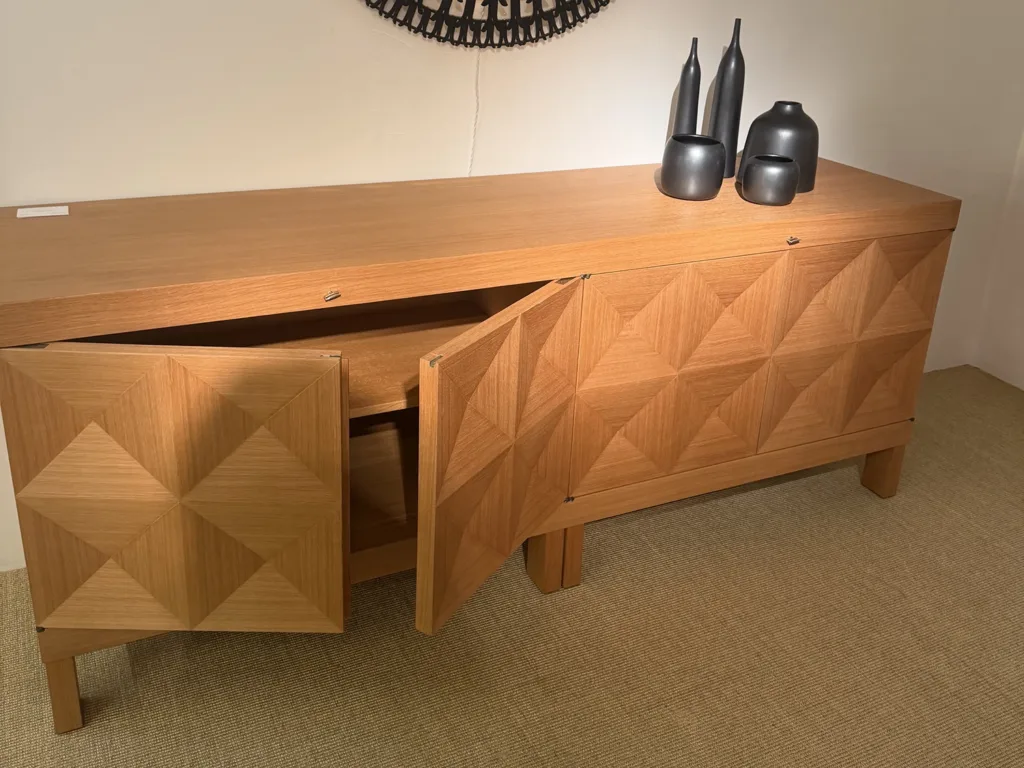 A vintage wooden credenza with brushed silver bottle-shaped decor sitting on top.