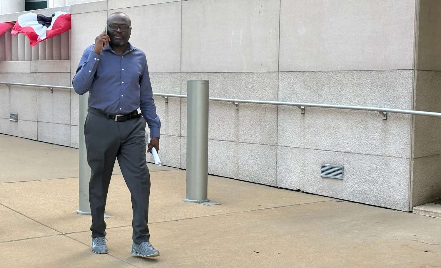 A man on a phone walks outside a courthouse.
