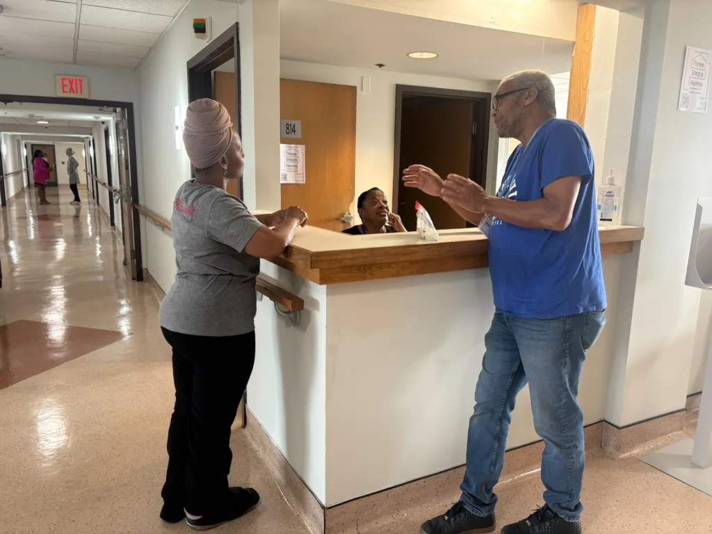 Three coworkers talk at a nurses' station.