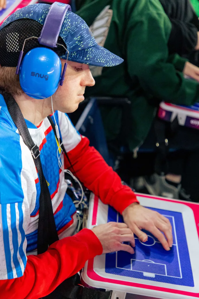 A fan wearing blue noise-reduction headphones uses an accessible tactile soccer experience device during a ST. Louis CITY SC match.