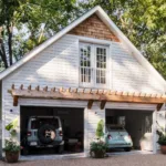 A craftsman style detached 2-car garage with a large window, cream-colored siding and light wood accents.