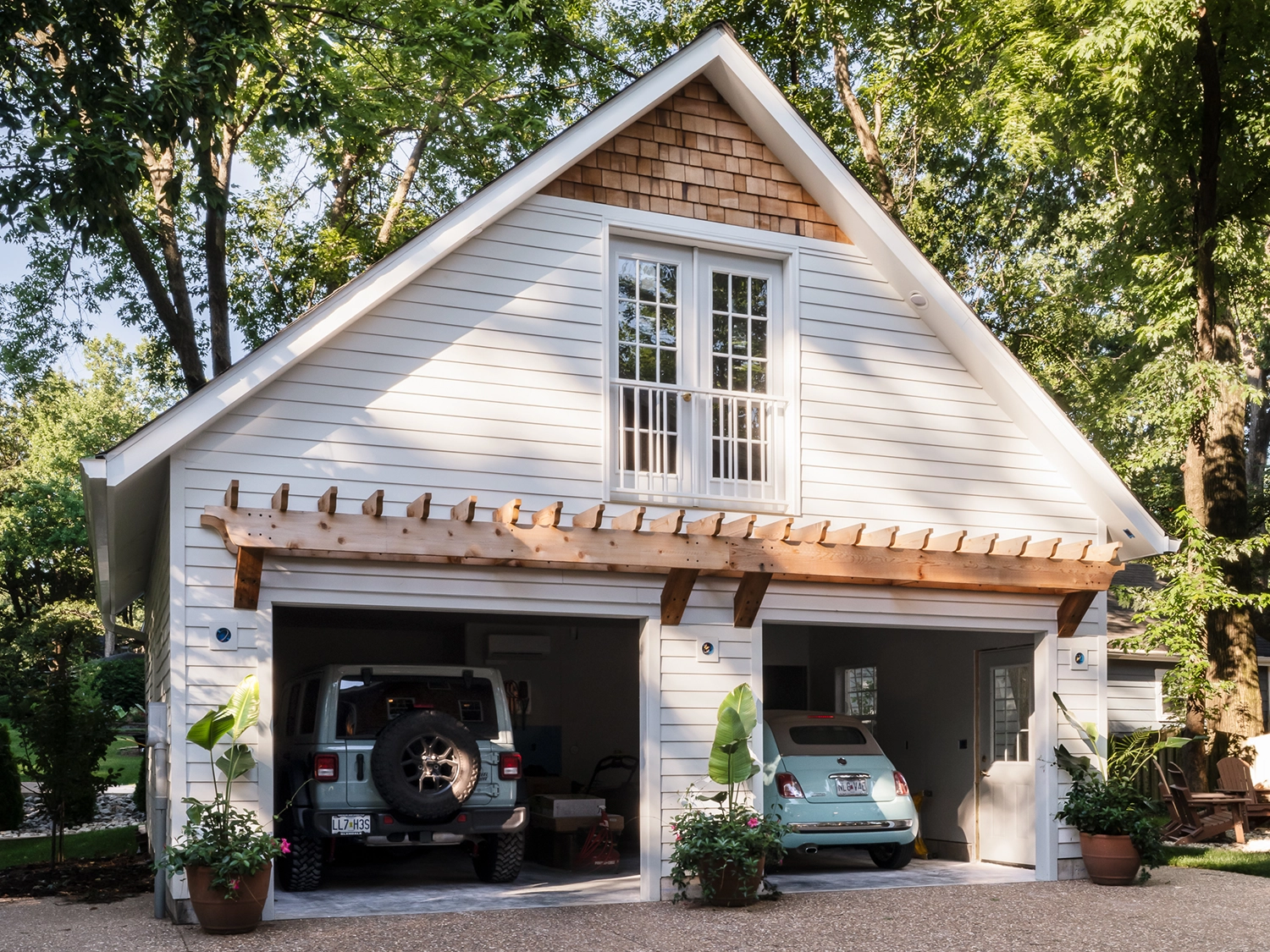 A craftsman style detached 2-car garage with a large window, cream-colored siding and light wood accents.
