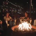 Guests gather around a fire at Old Glory Distilling Co.’s Silo Park.